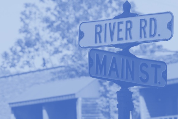 photo of street signs, one is Main St. and the other is River Rd.