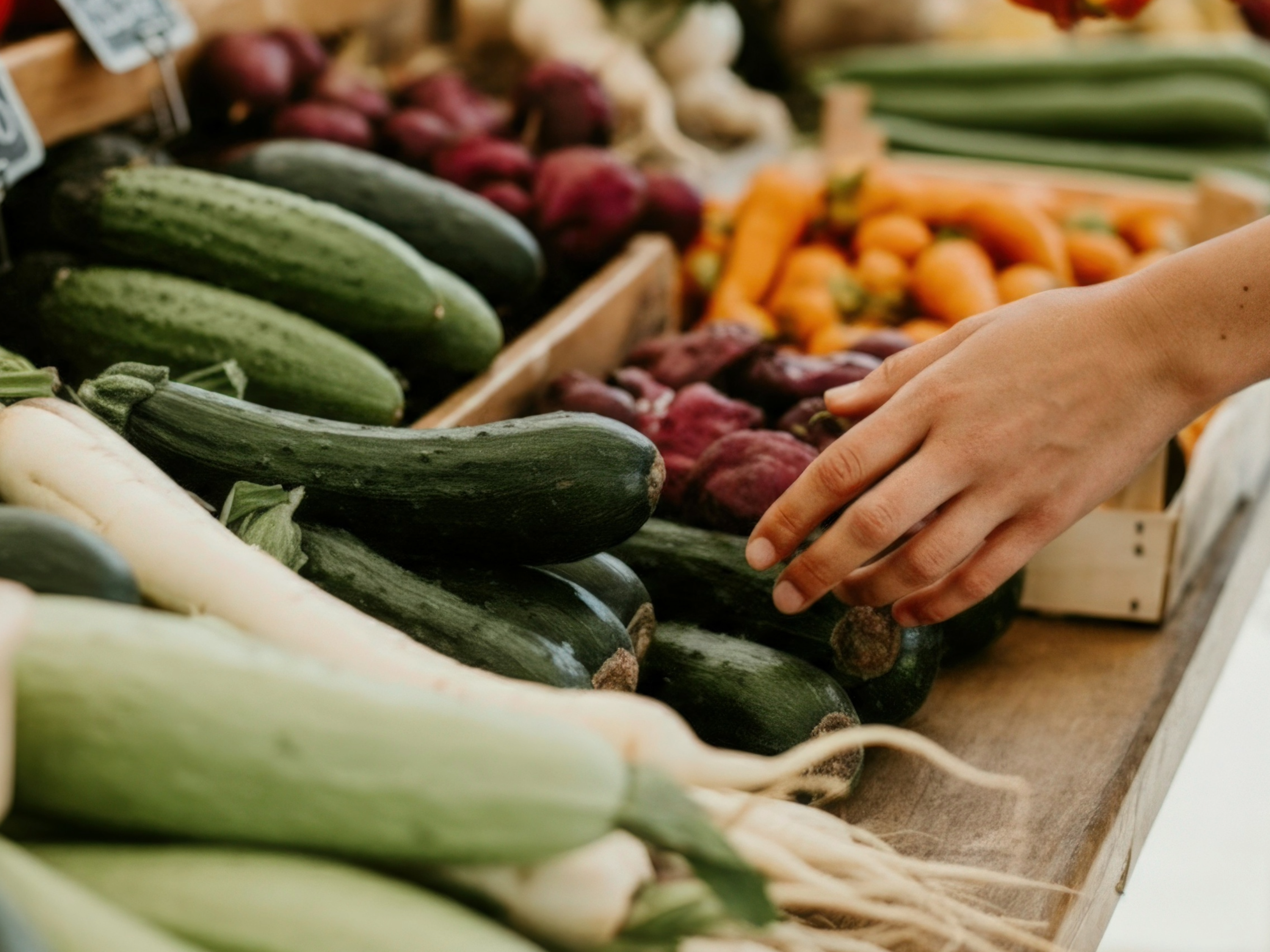 hand reaching for vegetables at farmers market